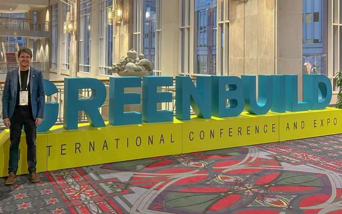 Un homme pose devant le logo de Green Building