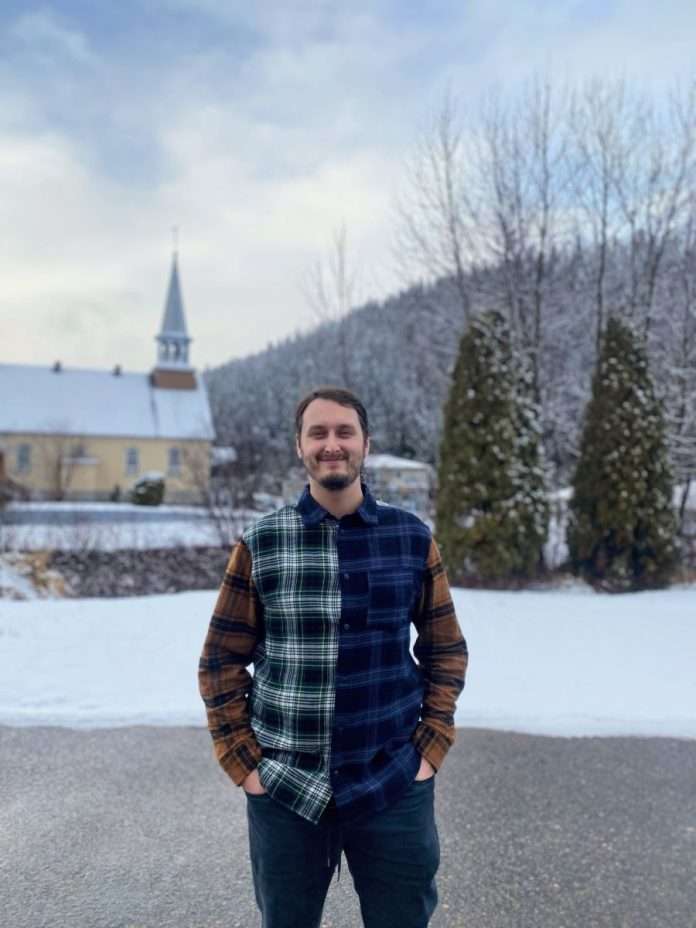 Un homme sourit devant l'église de Rivière-Éternité