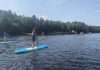 jeune faisant du paddle bor=ard sur un lac