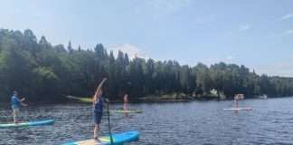 jeune faisant du paddle bor=ard sur un lac