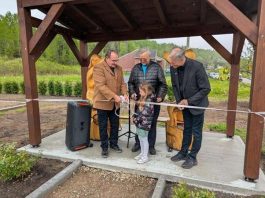 Un groupe de personnes s'apprête à coupe rle ruban lors d'une inauguration.