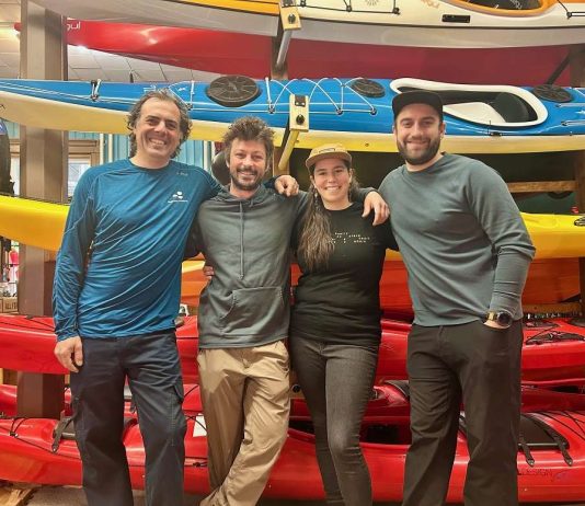 4 personnes sourient devant une pile de kayak