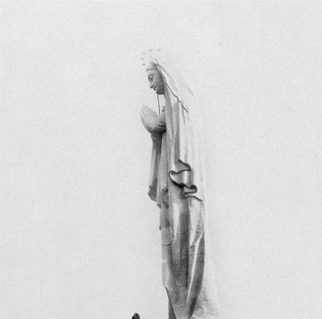 Un homme tout petit se tient au pied de la Statue Notre-Dame-du-Saguenay.