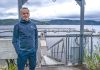 un homme pose les mains dans les poches devant la marina de L'Anse-Saint-Jean